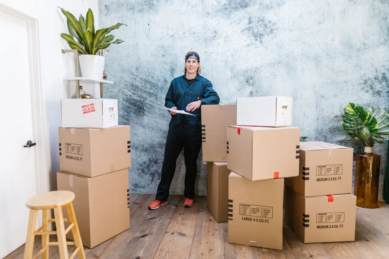 Mover with a clipboard checking an inventory beside packed boxes